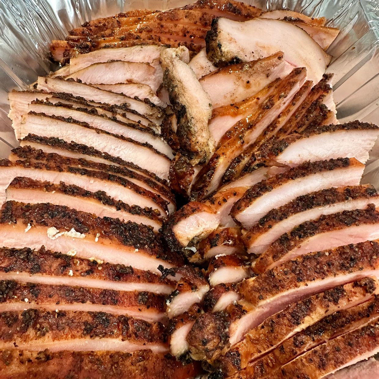 sliced up smoked turkey in an aluminum pan