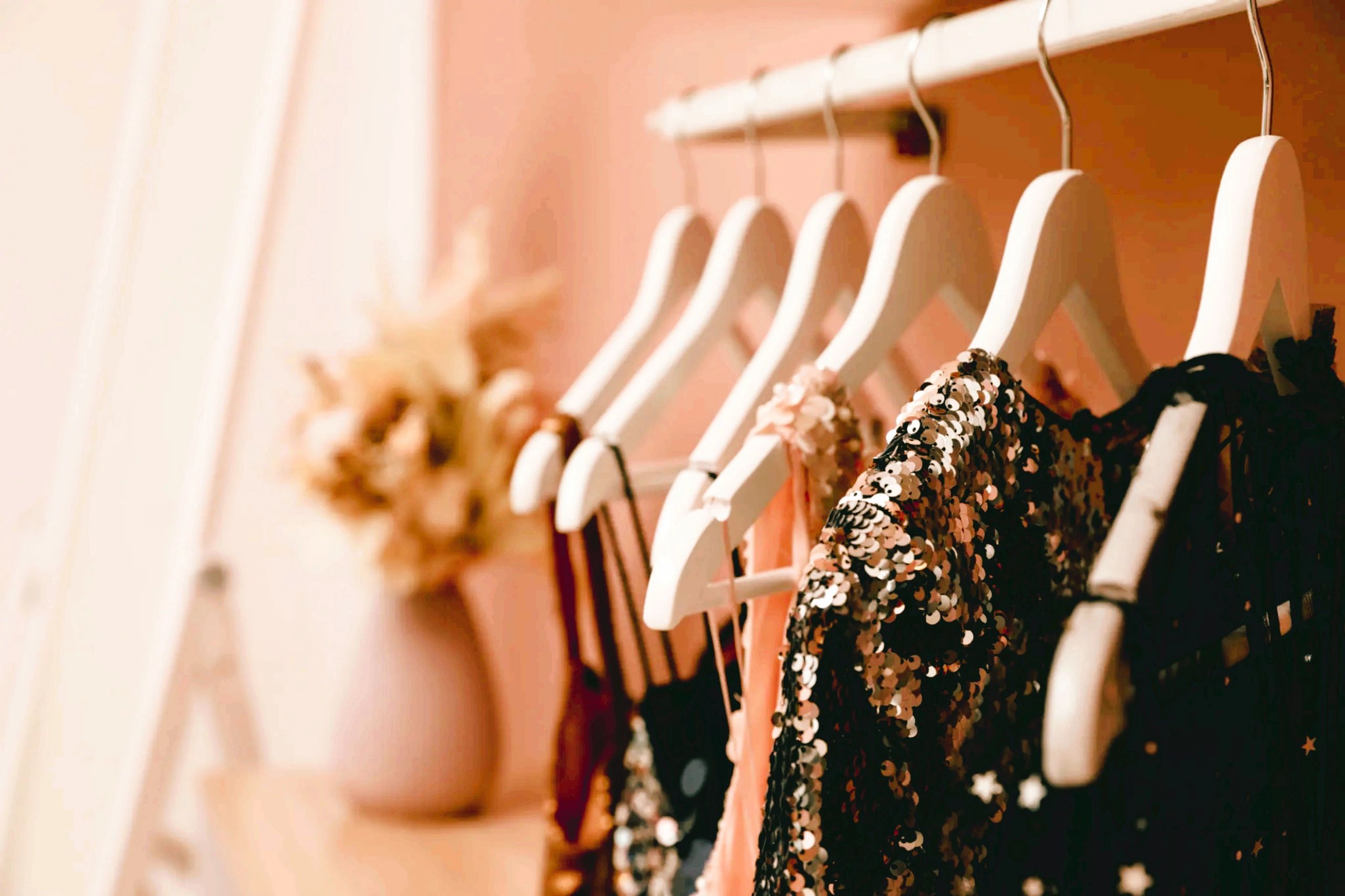 Elegant dresses hanging on white hangers in a softly lit room.
