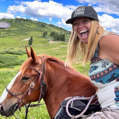 Woman joyfully riding a horse in a scenic field.