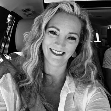 Smiling woman with wavy hair in a car.