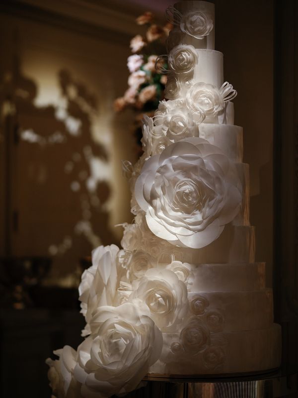 Elegant multi-tiered white wedding cake decorated with handcrafted rice paper roses and floral detai