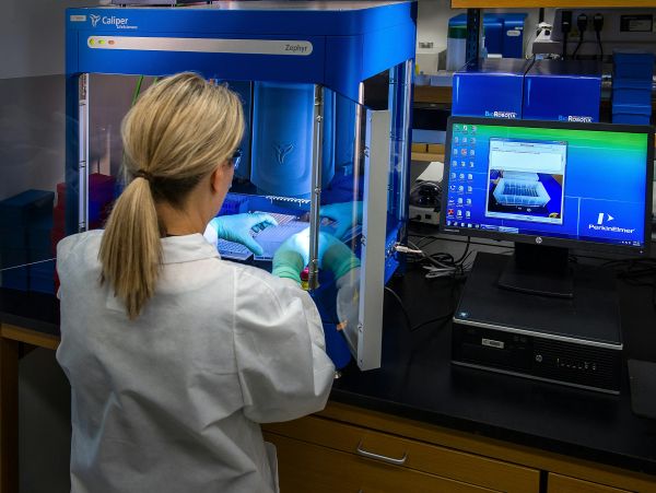 Scientist operating a Caliper Zephyr machine in a laboratory.