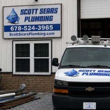 Scott Sears Plumbing sign and van outside a building.