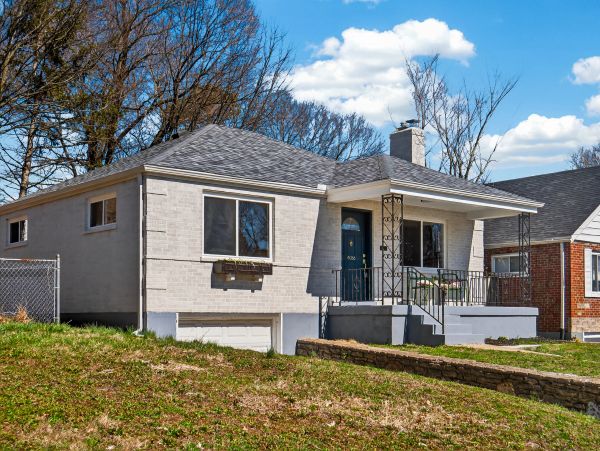 Single-story gray brick house with a small front porch and basement garage.