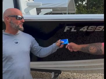 One person handing credit card to another person standing in front of a boat.