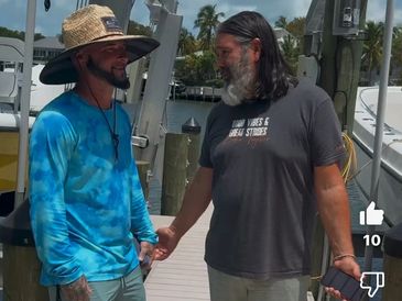 Two men talking on a boat dock and standing between two boats on lifts.