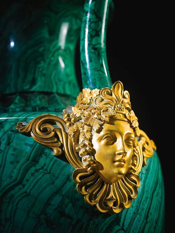 Golden decorative face on a green marble surface.
