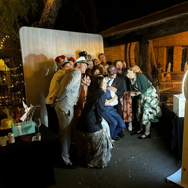 Group of people posing cheerfully in front of a photo backdrop at night.