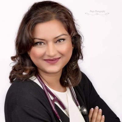 Confident female doctor with stethoscope smiles warmly, arms crossed.