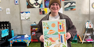 Person holding colorful artwork in a creative space.