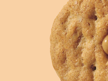 Close-up of a cookie sandwich with creamy filling against an orange background.