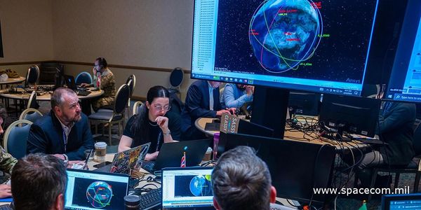 Team analyzing space data on multiple computer screens in a conference room.