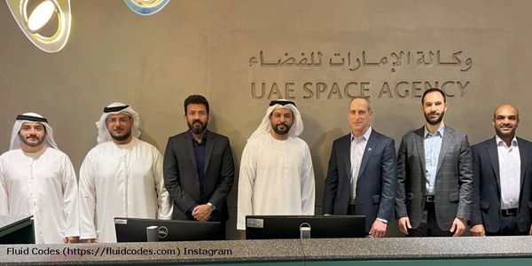 Seven men standing in front of the UAE Space Agency sign.