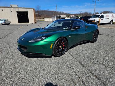 Green Lotus sports car parked outside on a sunny day.