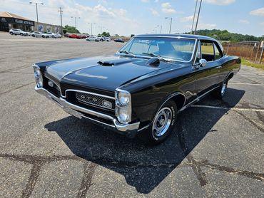 Classic black Pontiac GTO parked in a lot.