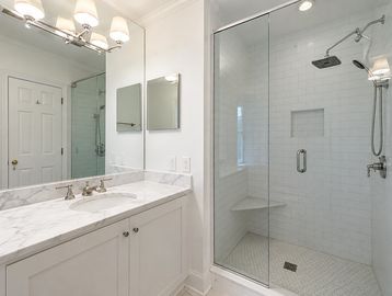 Modern bathroom with glass shower and marble countertop.