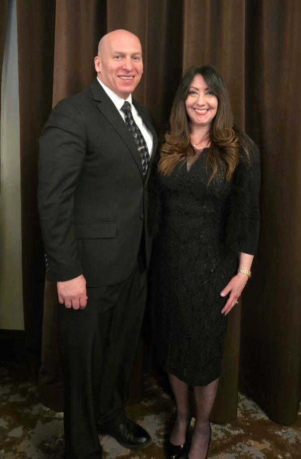Man and woman dressed formally, smiling.