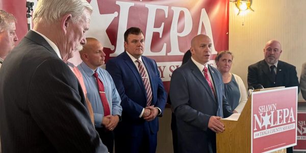 Group of people at a political event with a podium and sign.