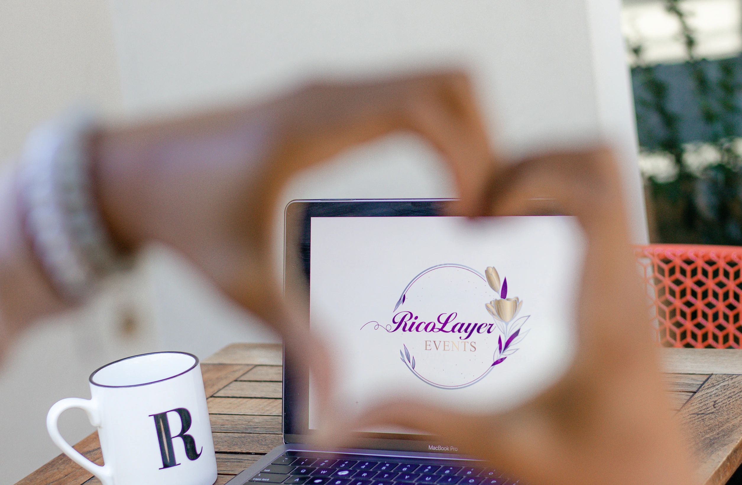 Woman holding up a heart in front of a laptop screen. 