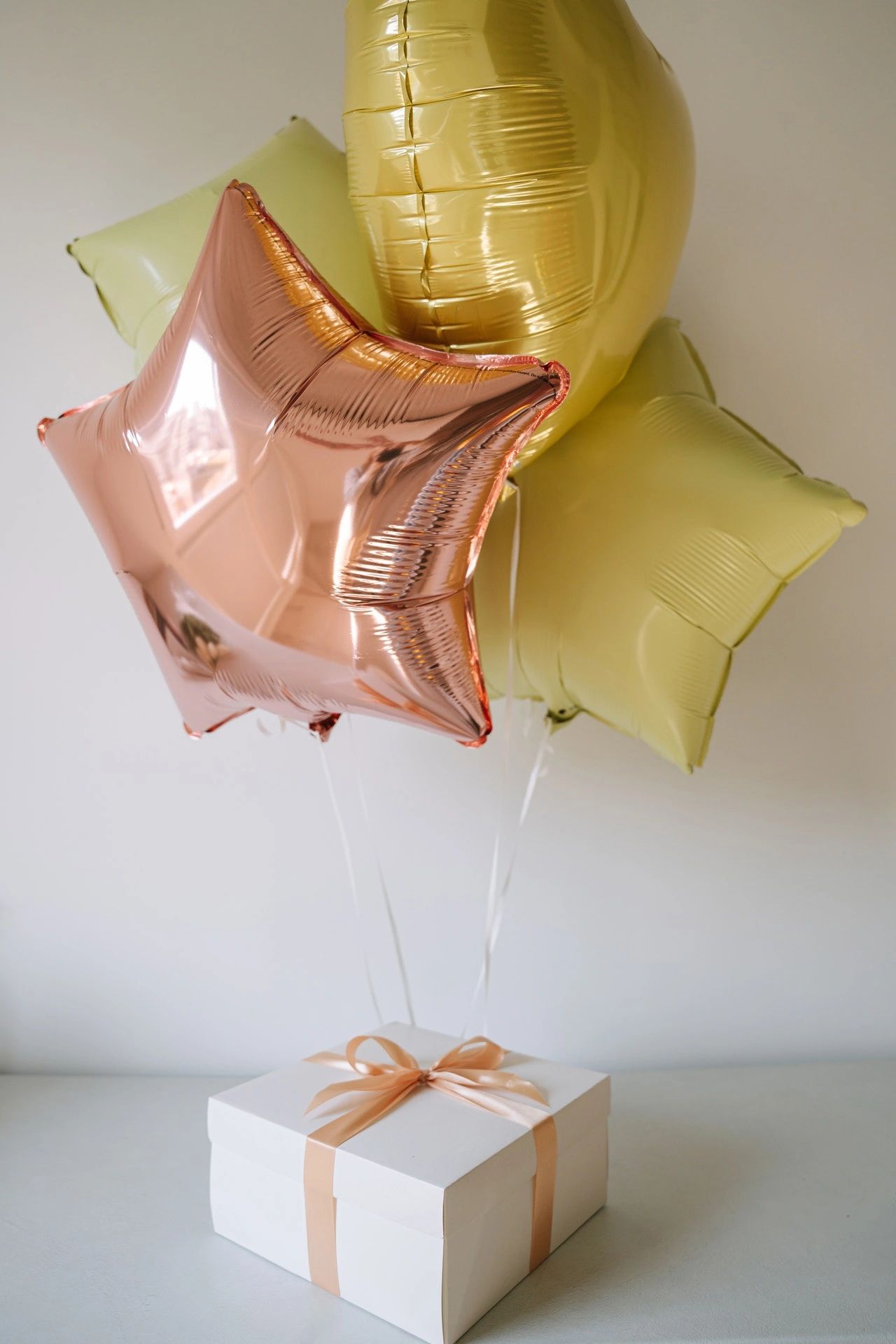 A cluster of balloons tied to a present box. 