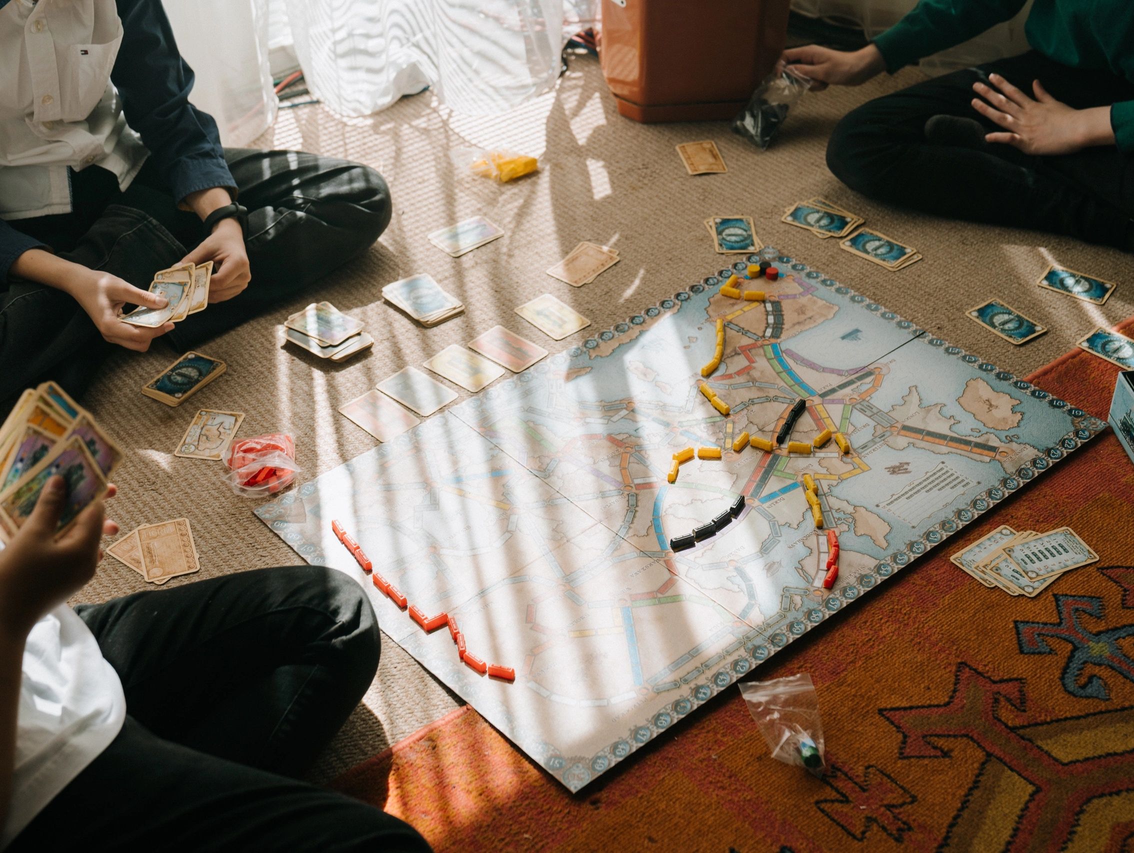 Group of people sitting and playing a board game. 