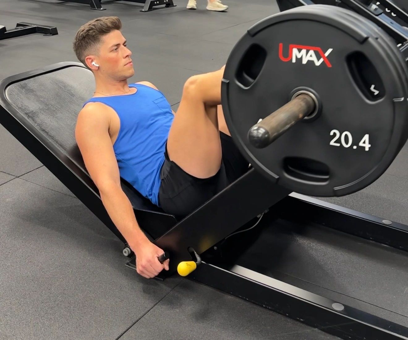 Man doing leg press exercise in a gym.