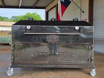 A large metal smoker with a Texas flag in the background.