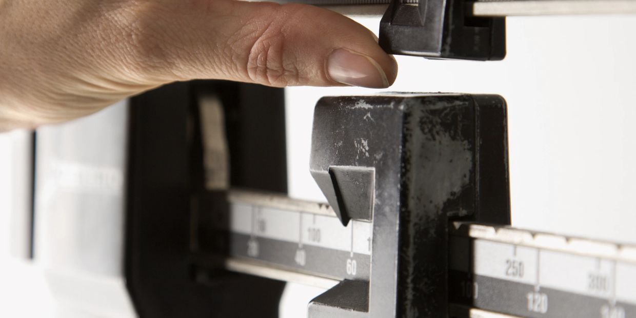 Hand adjusting a vintage mechanical balance scale.