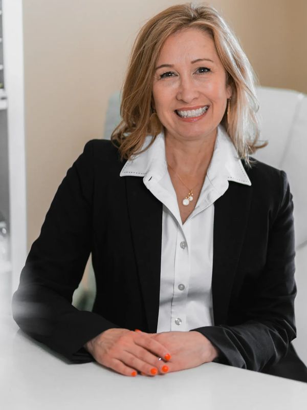 Smiling woman in business attire sitting at a desk.