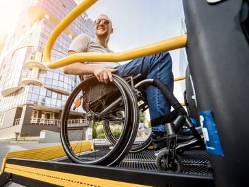 A man in a wheelchair on a lift of a vehicle for people with disabilities
