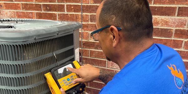 Technician checking air conditioner with digital gauge.