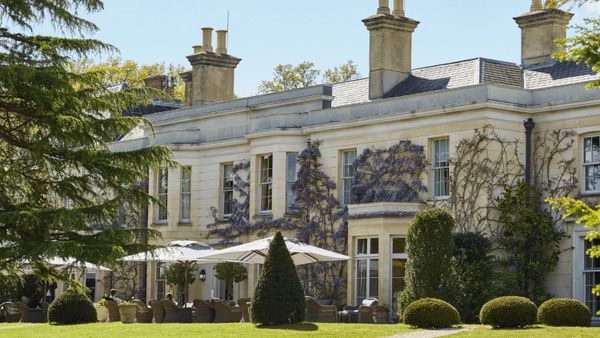 Elegant historic mansion with outdoor seating and lush garden.