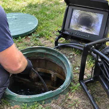 Worker inspecting a sewer line using a camera system.