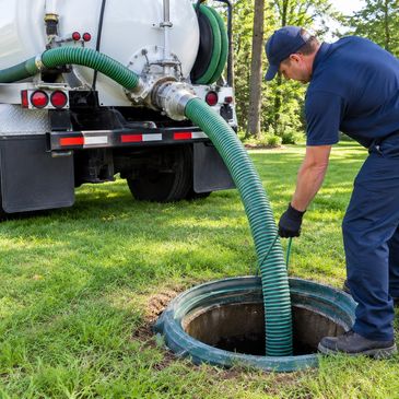 Worker cleaning a septic tank with a vacuum hose.