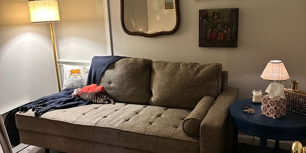 Cozy living room corner with a brown tufted sofa and warm lighting.