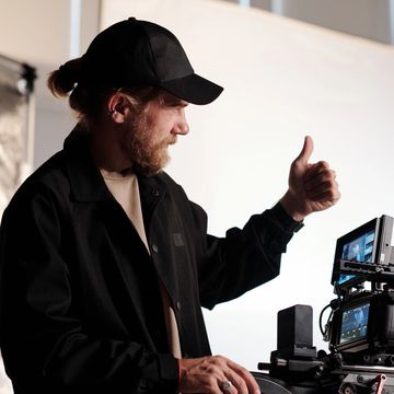 Director watching camera monitor. Man directing on a film set.