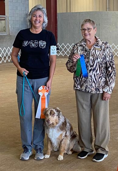 Two women with a dog and award ribbons.