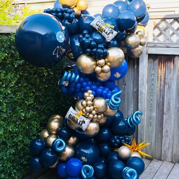 A vibrant balloon arrangement in blue, gold, and teal for a graduation celebration.