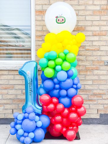 Colorful balloon arrangement with a blue number 1 and cartoon face balloon.