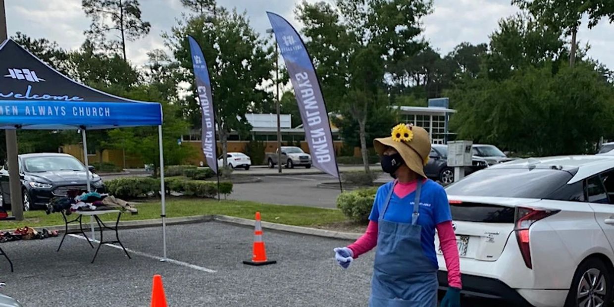 Woman in sun hat and mask at outdoor church event.