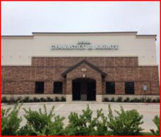 Exterior view of a gymnastics academy building with brick and beige facade.