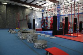 Indoor obstacle course with climbing walls and various fitness equipment.