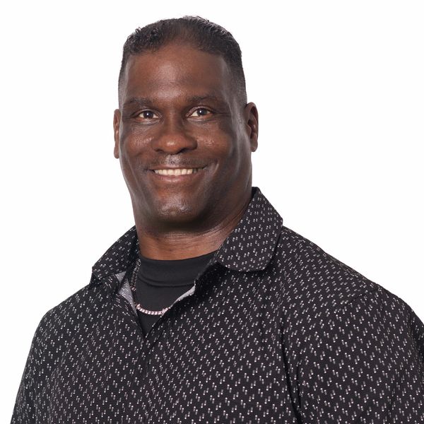 Smiling man in a patterned black shirt against white background.