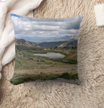 A throw pillow with the image of a mountain lake.