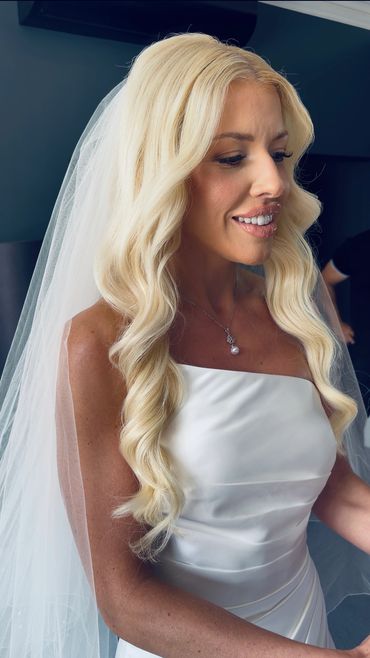 A bride with long blonde hair in a white wedding dress and veil.