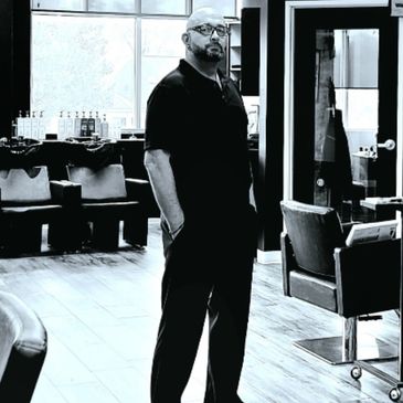 Man standing in a modern salon with large windows and chairs.