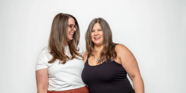 Two women smiling and standing close together.