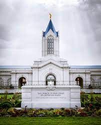 A white temple with a blue roof and an inscription in front.