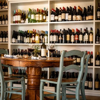 Cozy wine bar with wooden table and shelves full of wine bottles.