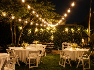 Outdoor garden party setup with string lights and decorated tables.